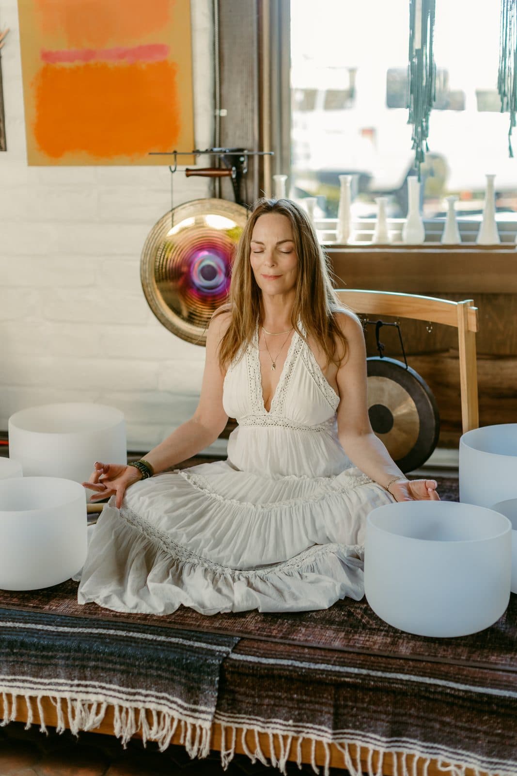 Miki seated on the floor among a set of crystal singing bowls