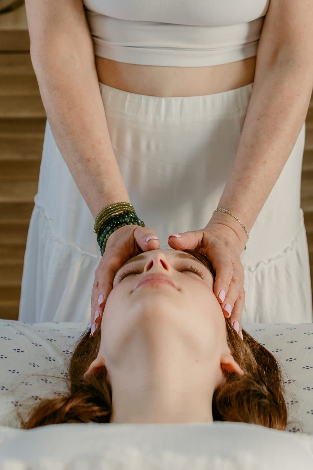 Miki's fingertips resting lightly on a client's forehead