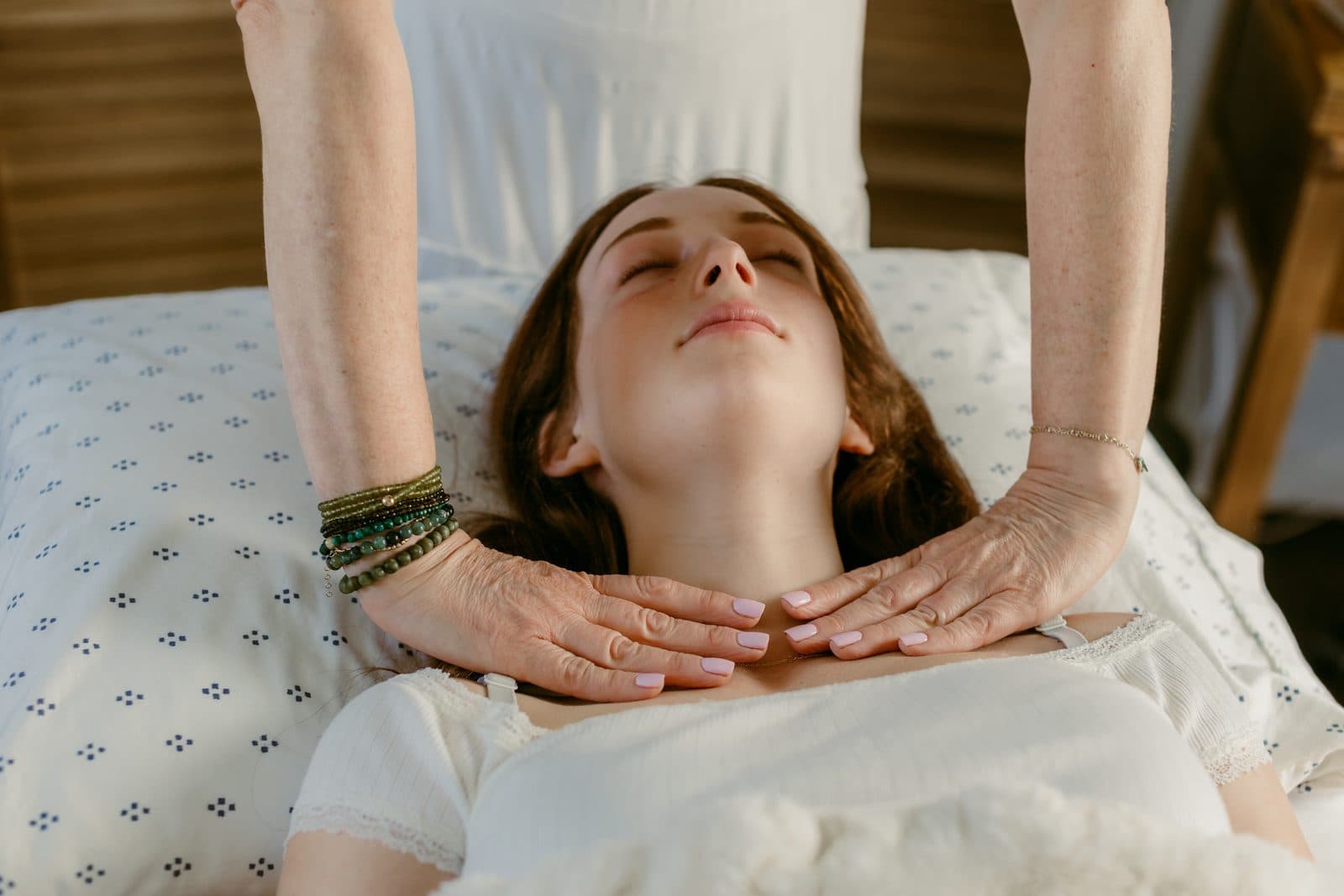 Miki's hands hovering just above a client's chest as she rests, fully clothed, on the table